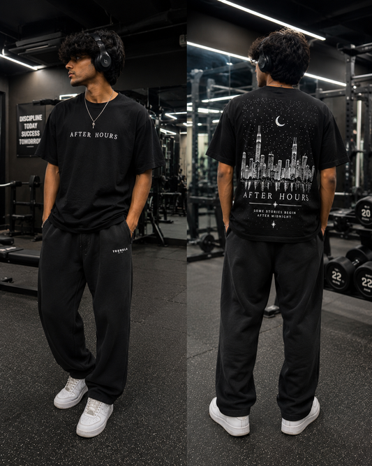 Person wearing a black 'After Hours' t-shirt with a cityscape design in a gym setting.