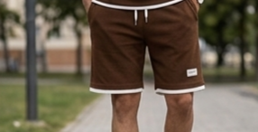 Brown shorts with a brand logo on a blurred outdoor background